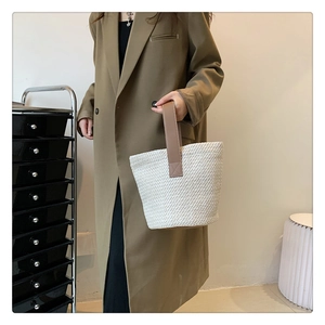 Detail of cream and brown woven knit bucket bag with premium brown leather handle