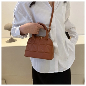 Detail of caramel quilted crossbody bag featuring unique geometric stitching and twin handles