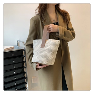 Close-up of beige woven bucket bag with brown leather handle and boho texture details
