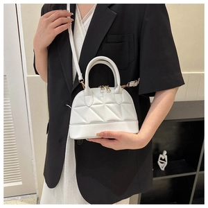 Close-up of a white shell-shaped handbag with quilted triangle patterns and gold hardware