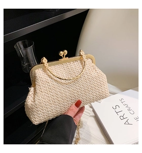 Detail of woven straw clutch bag with gold metal clasp and chain strap in cream white