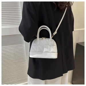 Close-up of a white quilted shell bag with gold hardware worn as a crossbody purse