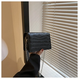 Detail of black crocodile pattern PU leather crossbody bag with silver chain strap