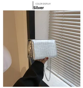Detail of silver crocodile-embossed mini square bag with shiny metal chain strap