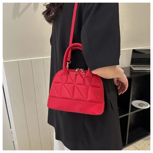Model wearing a red quilted shell bag with dual gold zippers and sleek nylon finish