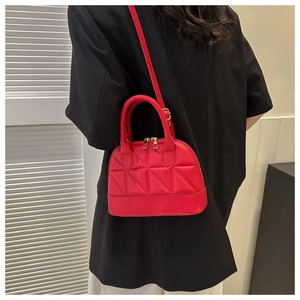 Close-up of red quilted leather shell bag with gold double zippers and stitching