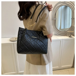 Model wearing black quilted PU leather shoulder bag with golden chain and Fashion logo
