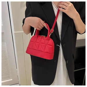 Close-up of red quilted mini handbag with geometric pattern and golden zippers