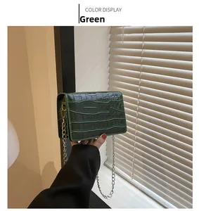 Detail of green faux crocodile texture on a small square bag with silver chain strap