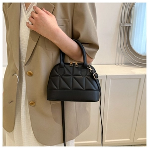 Detail of black quilted shell bag with gold zippers and detachable leather strap
