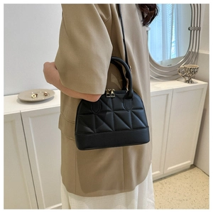 Close-up of black quilted leather crossbody bag with gold zippers and sleek handle