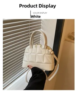 Detail of white quilted handbag featuring shell shape and golden metal zipper hardware