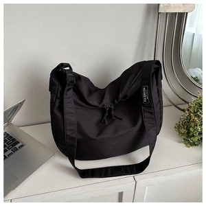 Détail du sac bandoulière croissant en nylon noir avec sangle et étiquette mode