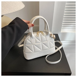 Close-up of white quilted handbag with golden zipper details and adjustable strap
