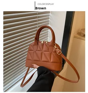 Close-up of brown quilted shell bag with gold hardware and curved handle