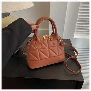 Detail shot of brown quilted leather texture and gold metal zipper on handbag
