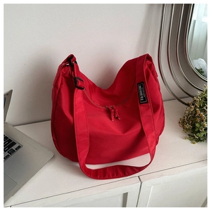 Détail du sac hobo en nylon rouge avec étiquette Fashion Instinct sur table blanche