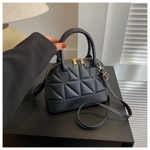 Close-up of quilted black handbag with gold hardware and stylish shell shape