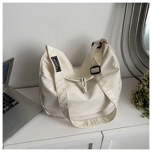 Détail du grand sac hobo en nylon blanc cassé avec bandoulière réglable et étiquette