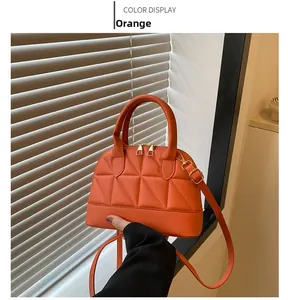 Close-up of orange quilted mini shell handbag with elegant gold zipper and handles