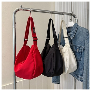 Sacs bandoulière demi-lune en nylon rouge, noir et blanc suspendus sur un support métal