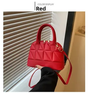 Macro detail of red quilted shell handbag featuring dual gold zippers and round handles