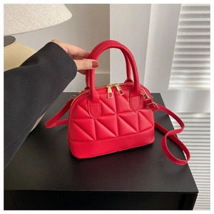 Detail of red quilted shell handbag with gold hardware and removable shoulder strap