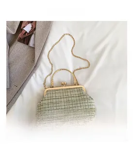 Detail view of green tweed shell bag with golden metal handle and ball-shaped clasp