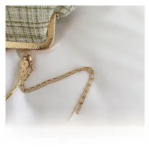 Close-up of green tweed texture with golden clasp and sunflower chain charm