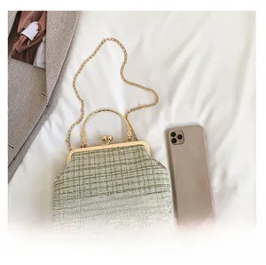Detailed view of a green plaid tweed clutch bag with golden handle and ball clasp closure
