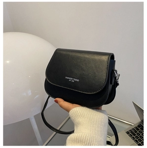 Detail view of black matte PU leather saddle bag with white lettering and silver hardware