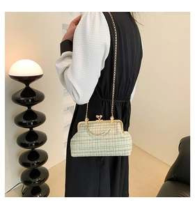 Detail of plaid tweed crossbody bag with golden chain strap on model in modern room