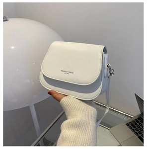 Detailed shot of white half-moon saddle bag with FASHION TREND text and smooth PU leather