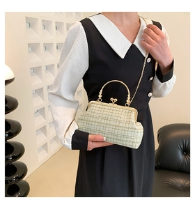 Detail of light green tweed shoulder bag with gold metal handle and ball clasp closure