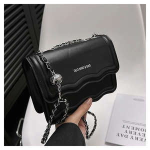 Detail of black leather shoulder bag featuring wavy edge flap and silver chain strap