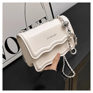 Detail of cream leather crossbody bag with wavy flap and silver chain strap ball