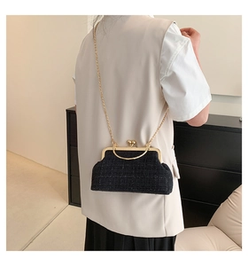 Rear view of a black tweed crossbody frame bag with gold hardware and chain strap