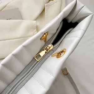 Detail view of the smooth gold zipper and stitching on a white quilted crossbody bag