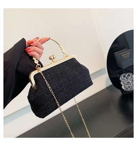 Detail of black tweed evening clutch with gold metal frame and spherical clasp handle