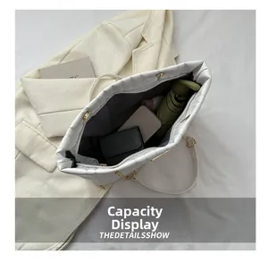 Spacious interior of white quilted tote bag holding a wallet, gadgets, and folded umbrella
