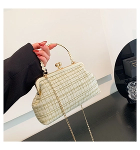 Detail of tweed crossbody bag featuring gold hollow-out handle and vintage clasp