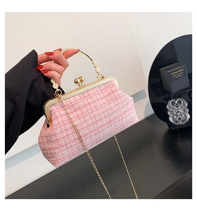 Detail of pink and white tweed bag featuring a golden floral handle and chain strap
