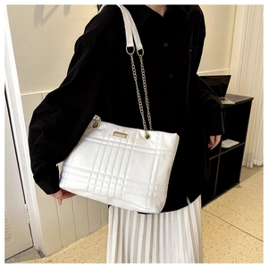 Detailed view of white quilted faux leather tote bag with elegant gold chain strap