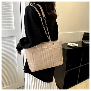Detail of beige quilted leather tote bag showing large capacity and chain shoulder strap