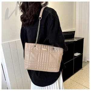 Detailed back view of a beige quilted tote bag with golden chain strap on a model