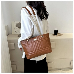 Detail of brown quilted tote bag with leather and gold chain shoulder strap