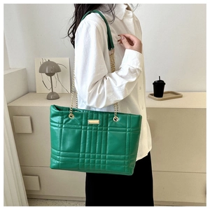 Detailed view of green quilted leather bag with gold chain strap worn by a model