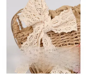 Detail of woven straw bag featuring large cream lace bow and daisy floral decoration