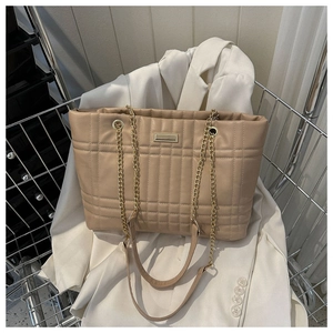 Detail of beige quilted tote bag with golden chain strap and soft leather texture