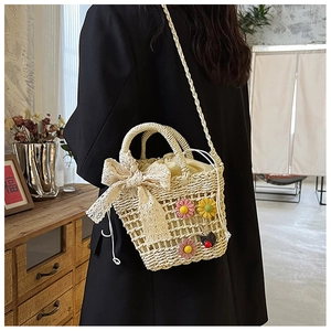 Detail of woven straw bucket bag featuring lace bow and floral charms in a cozy setting